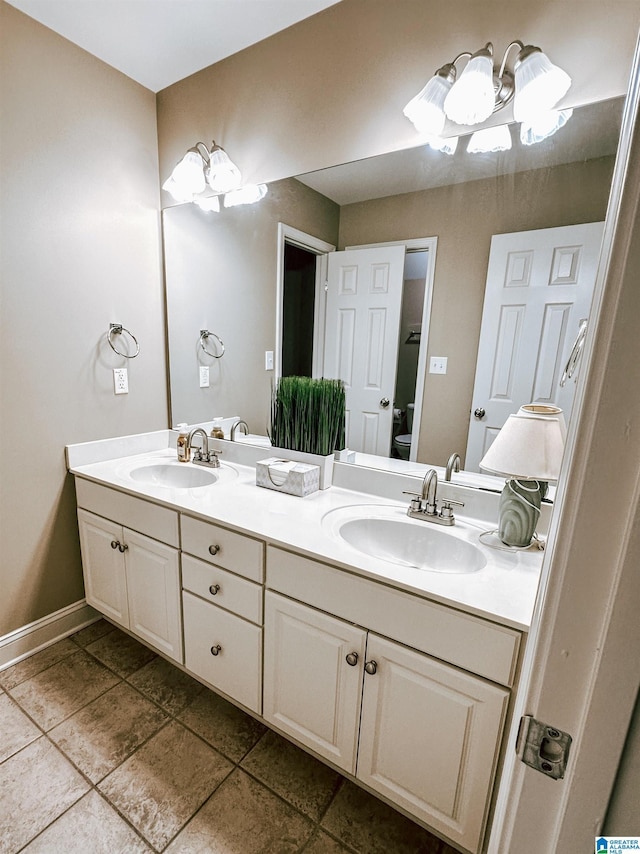 bathroom featuring double vanity, toilet, baseboards, and tile patterned floors