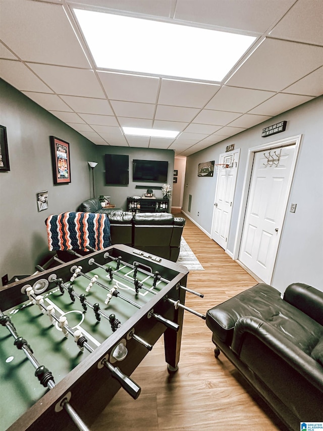 game room with light wood-type flooring, a drop ceiling, and baseboards
