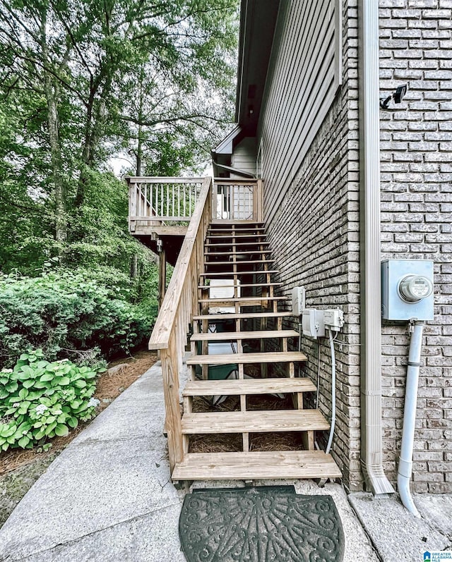 entrance to property featuring a wooden deck and brick siding