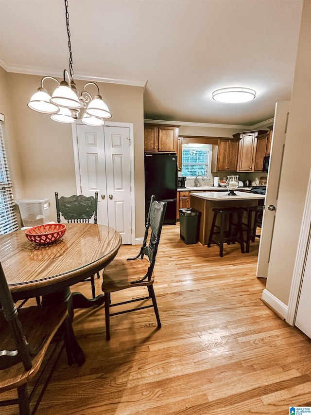 dining room featuring ornamental molding, light wood-style flooring, a chandelier, and baseboards