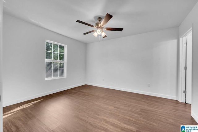 empty room with baseboards, a ceiling fan, and dark wood finished floors