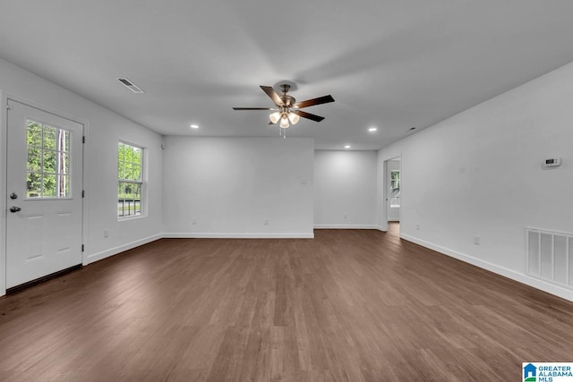 unfurnished living room featuring visible vents, a ceiling fan, baseboards, and wood finished floors