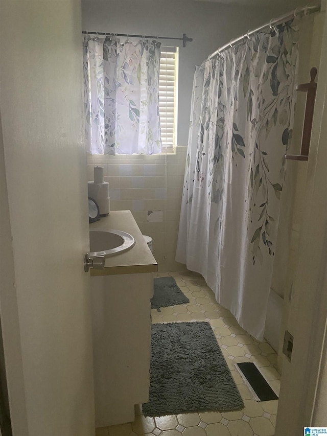 bathroom with vanity, tile patterned floors, tile walls, and curtained shower