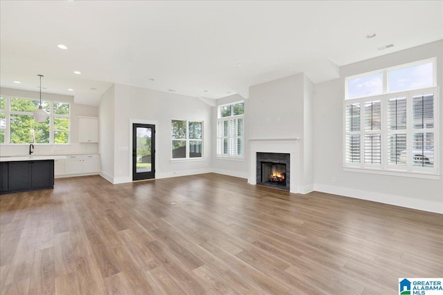 4546 Brexton St, Trussville, AL 35173 - unfurnished living room featuring a lit fireplace, plenty of natural light, and light wood-style flooring