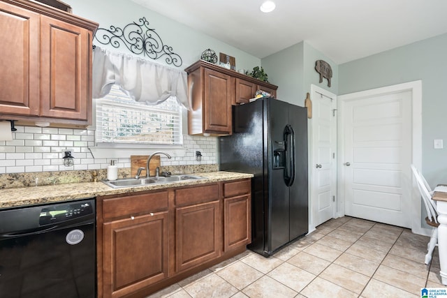 kitchen featuring light stone counters, a sink, light tile patterned floors, backsplash, and black appliances