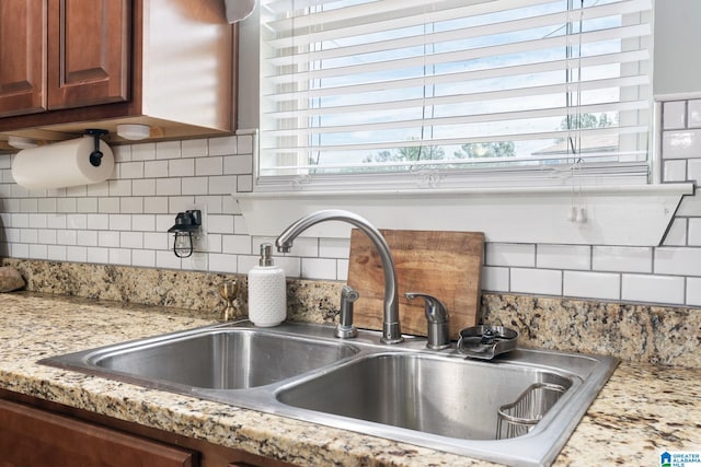 interior details with a sink, backsplash, and brown cabinets