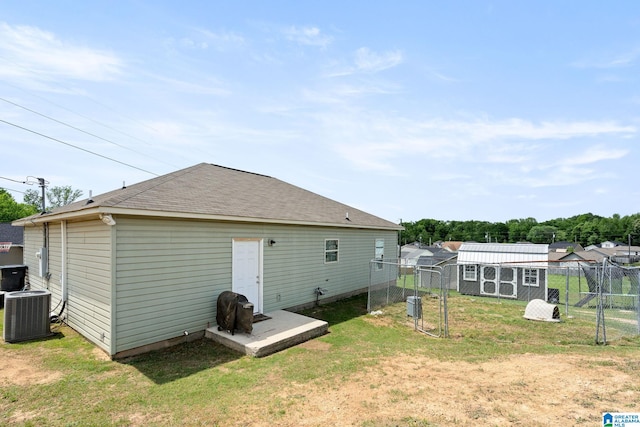back of house featuring an outdoor structure, fence, a yard, and cooling unit