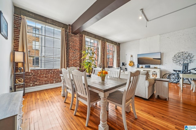 dining space featuring brick wall, light wood-type flooring, beam ceiling, and baseboard heating
