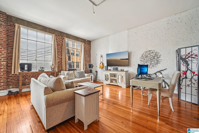 living area with hardwood / wood-style floors and brick wall