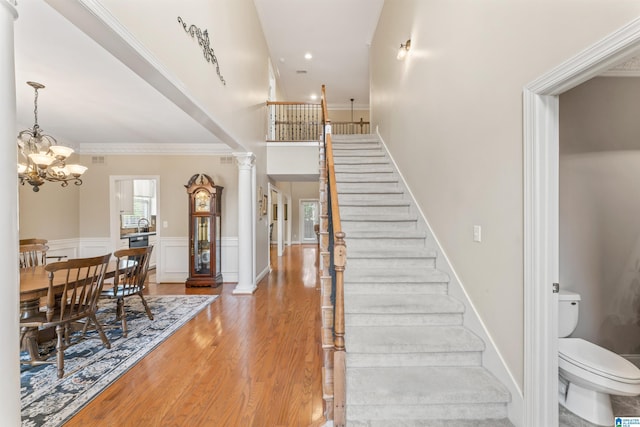 2608 Arbor Way, Hoover, AL 35244 - staircase with wood finished floors, crown molding, ornate columns, wainscoting, and a chandelier