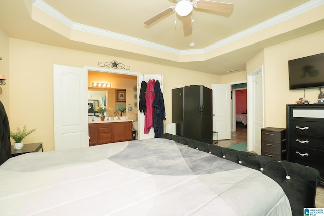 bedroom featuring ornamental molding, connected bathroom, a ceiling fan, and a raised ceiling
