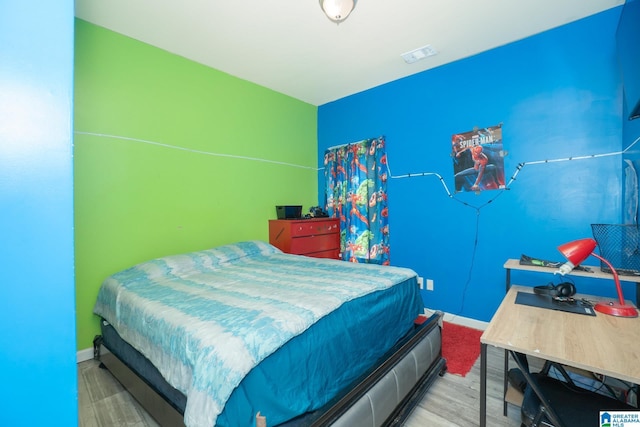 bedroom featuring baseboards, visible vents, and wood finished floors
