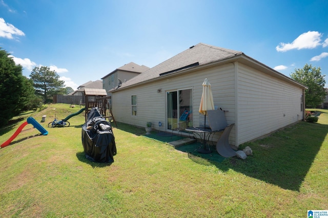 rear view of house with fence and a lawn