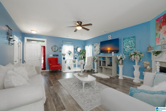 living area with baseboards, wood finished floors, a ceiling fan, and a fireplace