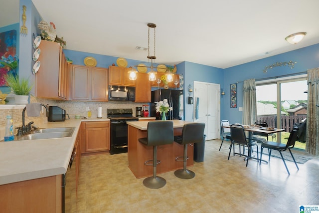 kitchen with a sink, tasteful backsplash, black appliances, light countertops, and a center island