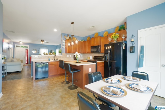 kitchen featuring a peninsula, a sink, brown cabinetry, black appliances, and light countertops