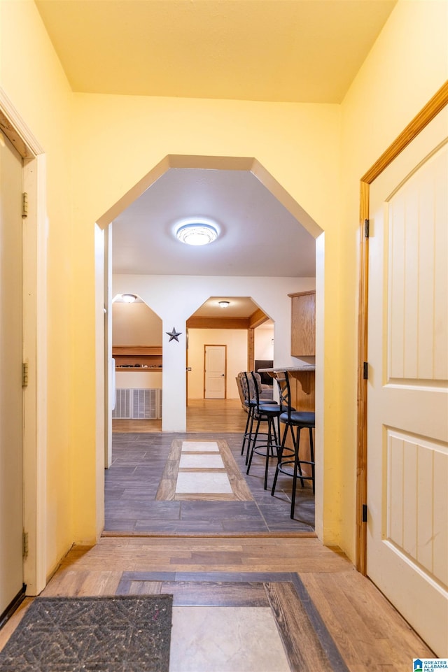 hall featuring arched walkways and wood finished floors