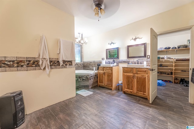 full bathroom with wood finished floors, vanity, a bath, and ceiling fan with notable chandelier