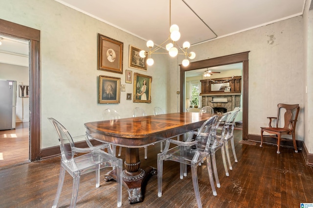 dining room with hardwood / wood-style floors, a fireplace, baseboards, crown molding, and a ceiling fan