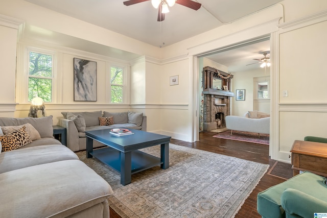 living area with ceiling fan, a fireplace, wood finished floors, and a decorative wall