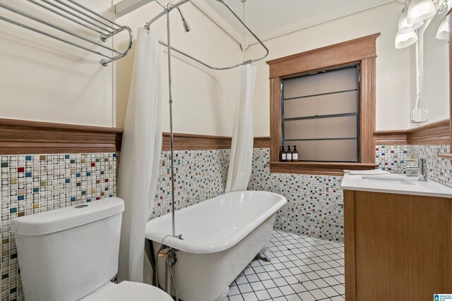 full bath featuring tile walls, a soaking tub, tile patterned flooring, toilet, and a wainscoted wall