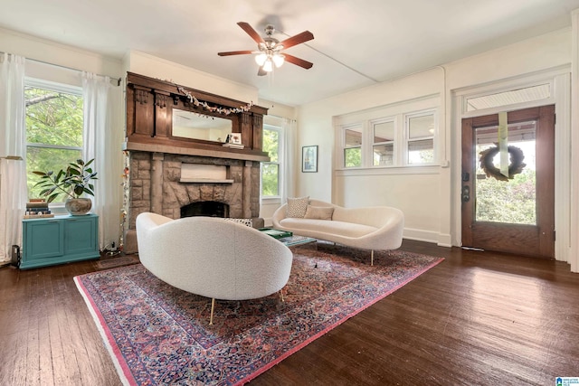 living area featuring ceiling fan, dark wood-style flooring, and a fireplace