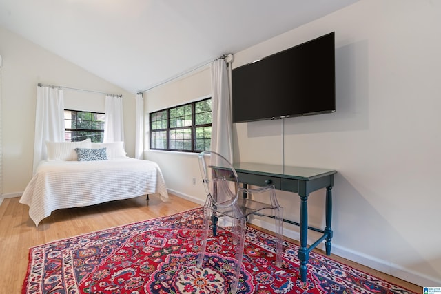 bedroom with wood finished floors, baseboards, and vaulted ceiling