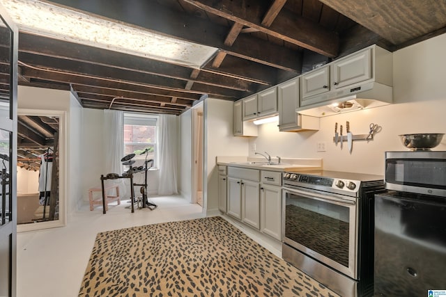 kitchen featuring appliances with stainless steel finishes, under cabinet range hood, a sink, light countertops, and light tile patterned floors
