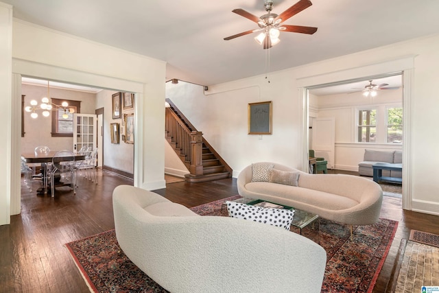 living area with a ceiling fan, dark wood-type flooring, stairs, a chandelier, and crown molding