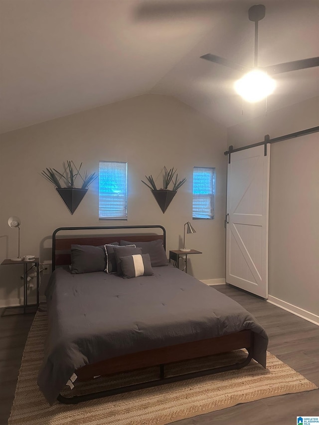 bedroom with a ceiling fan, a barn door, baseboards, vaulted ceiling, and dark wood-style floors