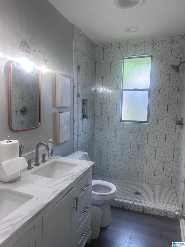 bathroom featuring toilet, wood finished floors, a stall shower, and a sink