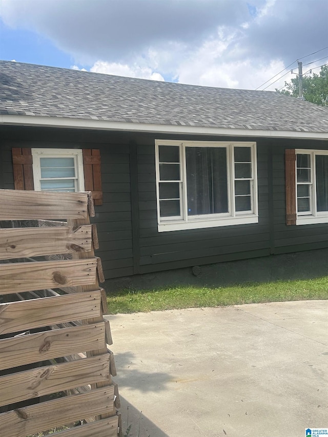 entrance to property with a patio and roof with shingles