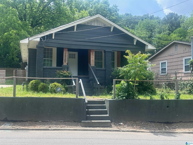 bungalow-style home with a porch, fence, and stairs