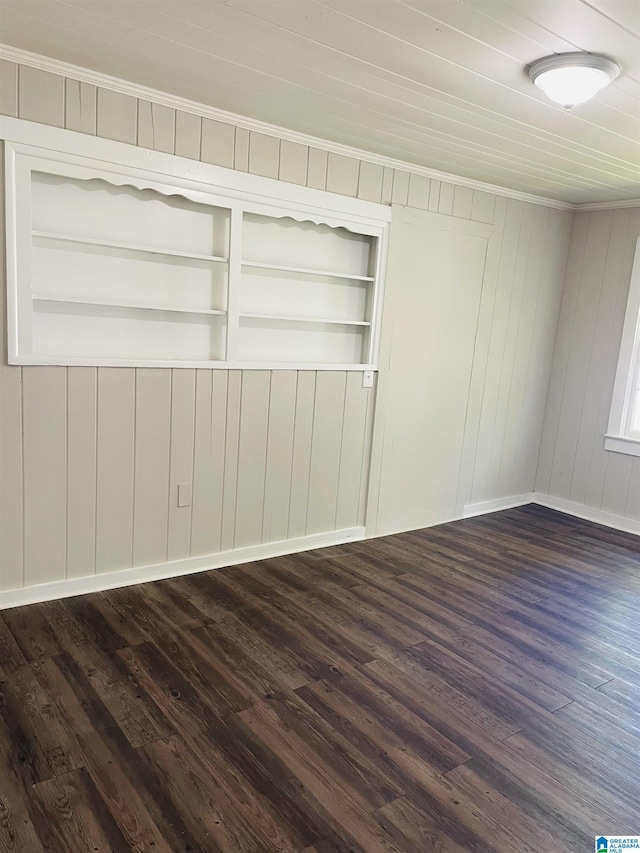 unfurnished room with crown molding, built in features, and dark wood-type flooring
