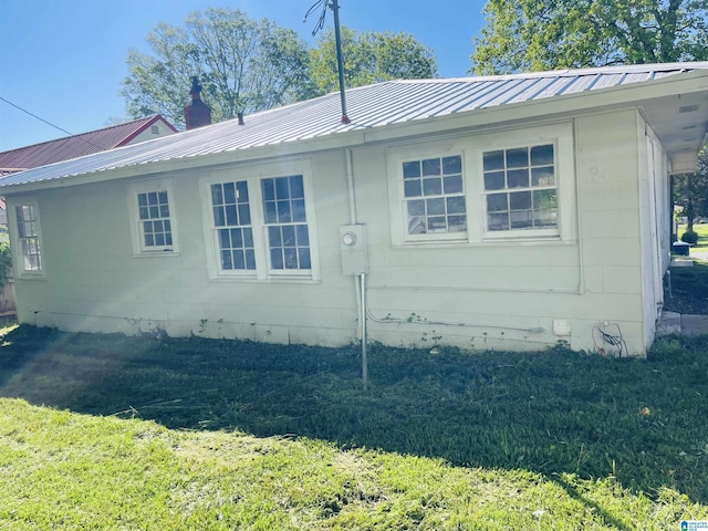 view of side of home with metal roof and a lawn
