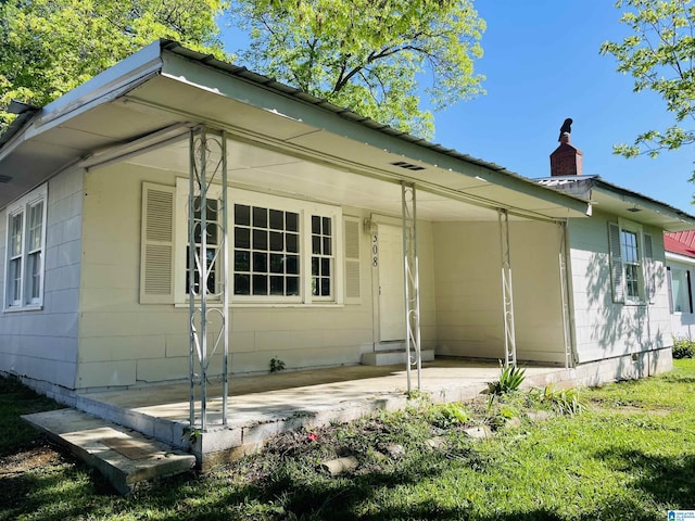 view of front of property with a chimney, entry steps, and an attached carport