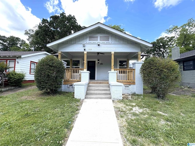 bungalow-style house featuring board and batten siding, covered porch, and a front lawn
