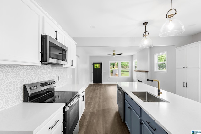 kitchen with appliances with stainless steel finishes, a sink, dark wood-style floors, open floor plan, and decorative backsplash