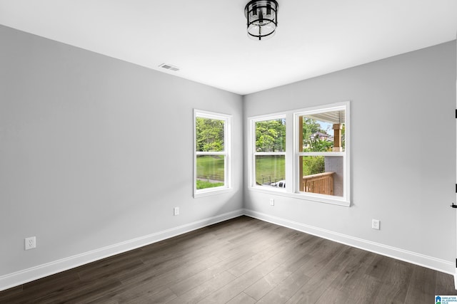 spare room with baseboards and dark wood-type flooring