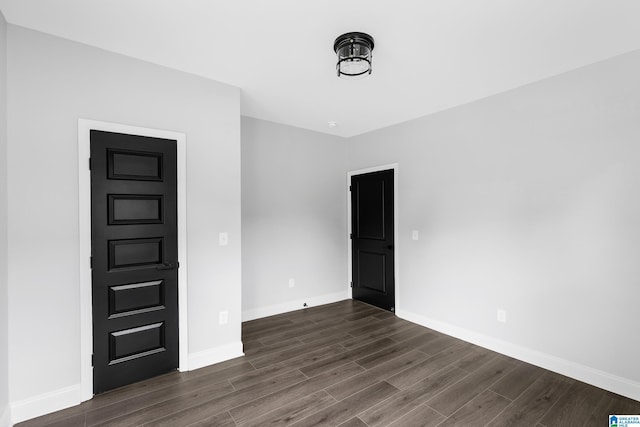 spare room with dark wood-type flooring and baseboards