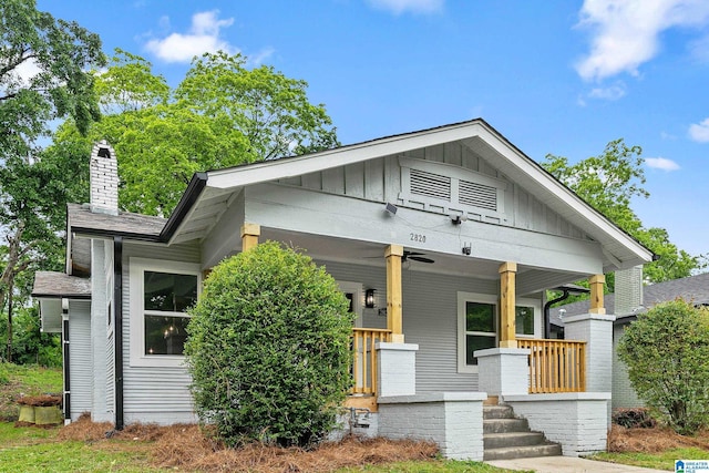 view of front of home with a chimney, a porch, board and batten siding, and a shingled roof