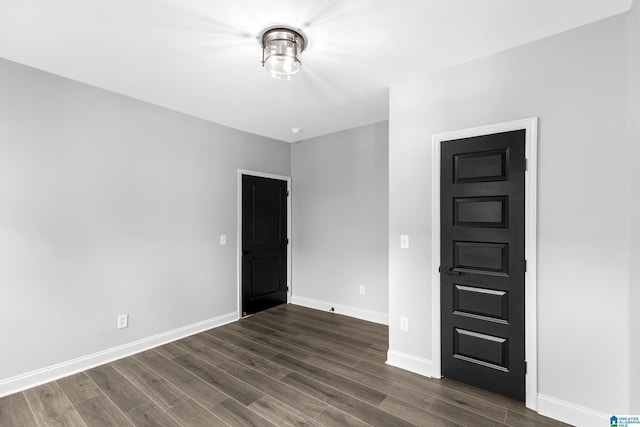 unfurnished room featuring dark wood-style flooring and baseboards