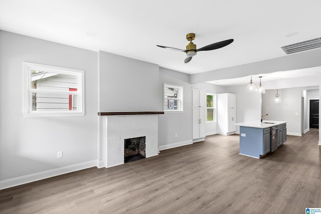 unfurnished living room with ceiling fan, a fireplace, dark wood-style floors, and baseboards