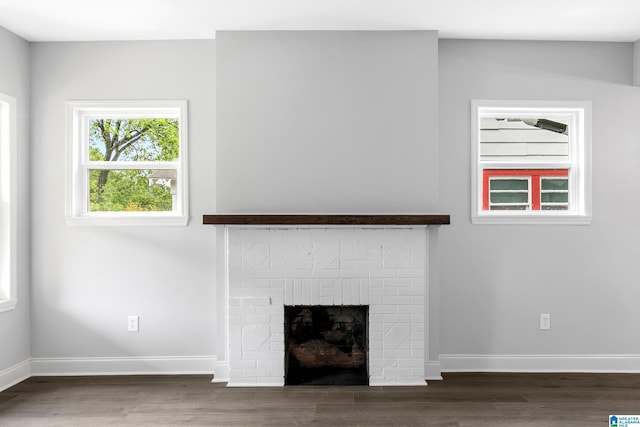 detailed view of a brick fireplace, wood finished floors, and baseboards