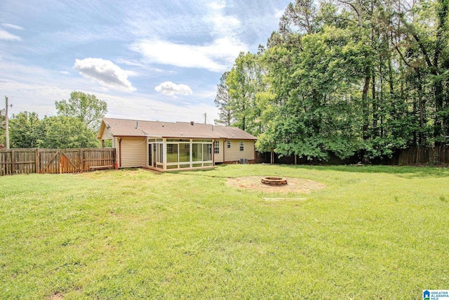 view of yard featuring an outdoor fire pit, a sunroom, and a fenced backyard