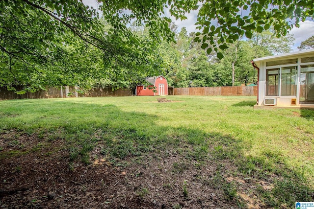 view of yard with an outbuilding, a sunroom, a fenced backyard, and a storage unit