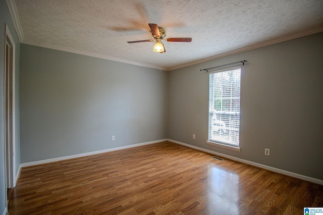 empty room featuring a ceiling fan, a textured ceiling, baseboards, visible vents, and wood finished floors