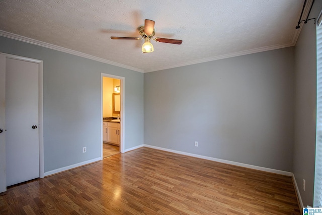 unfurnished bedroom featuring baseboards, ornamental molding, light wood-style flooring, and a textured ceiling