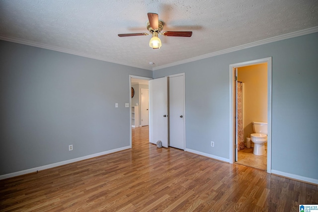 unfurnished bedroom with connected bathroom, a textured ceiling, wood finished floors, and baseboards