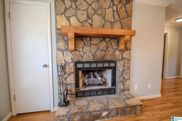 details featuring ornamental molding, baseboards, a stone fireplace, and wood finished floors